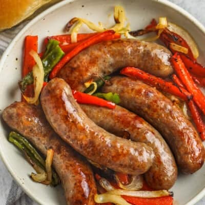 top view brats with peppers and onions on a plate
