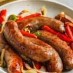 brats with peppers and onions on a plate