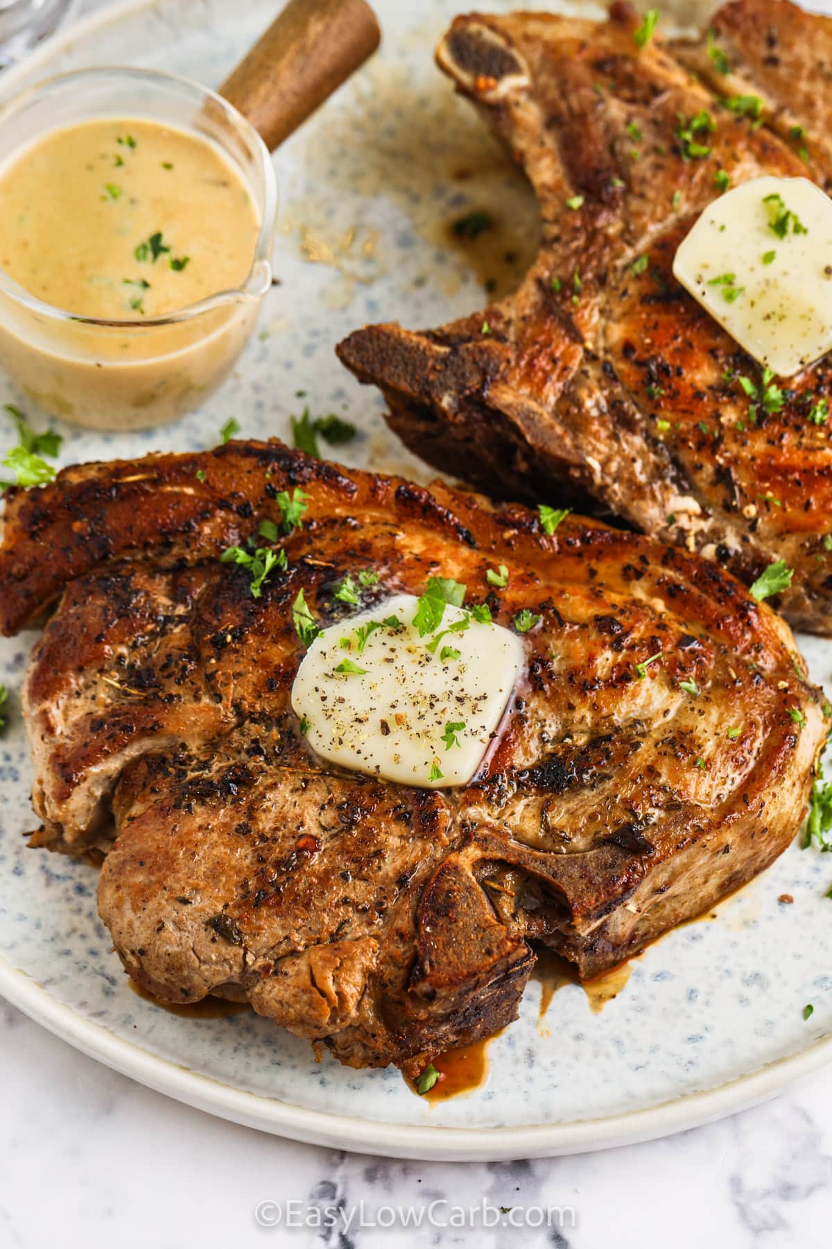 Creamy Skillet Pork Chops on a plate with a side of sauce