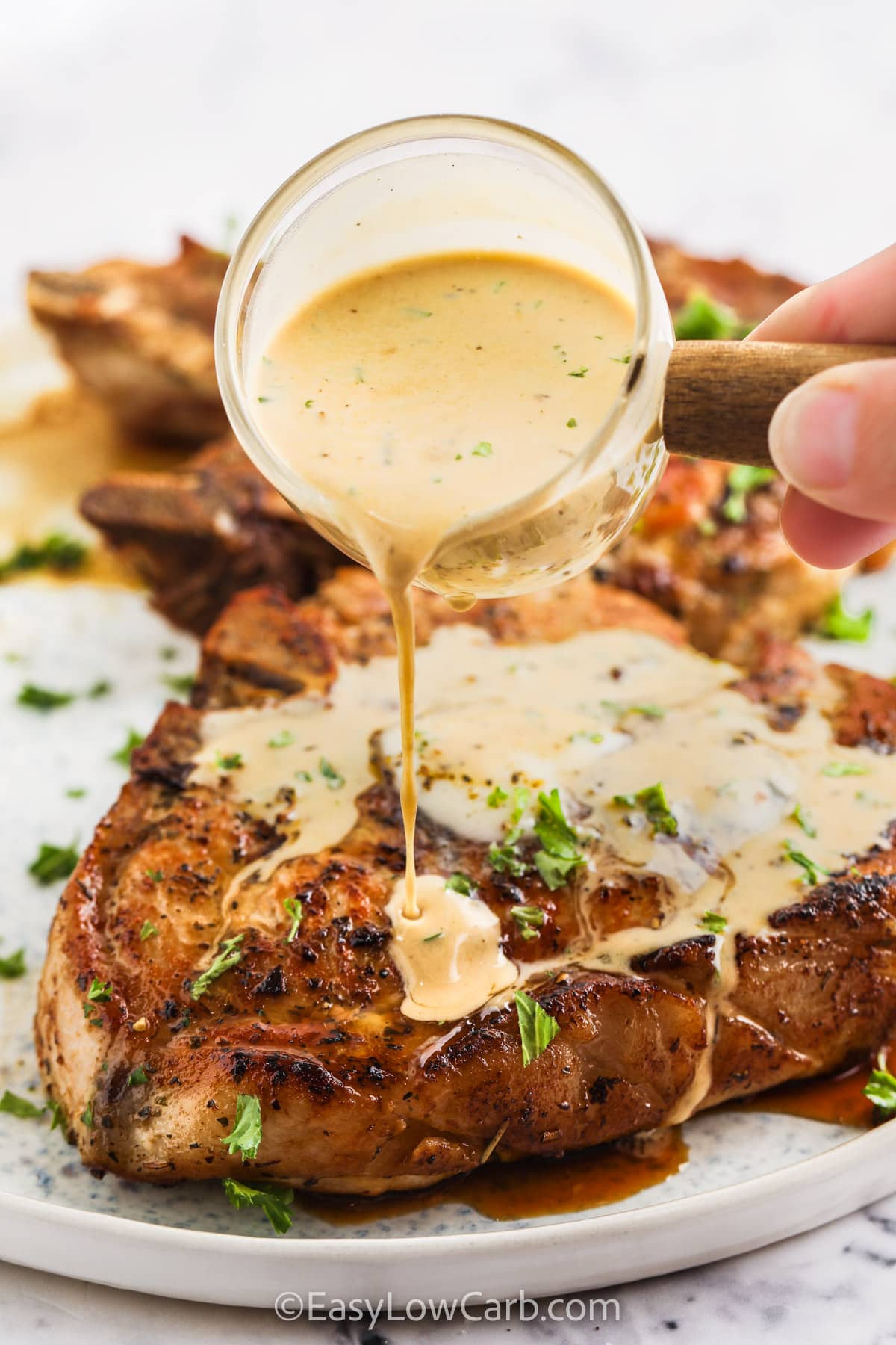 Creamy Skillet Pork Chops with sauce being poured on