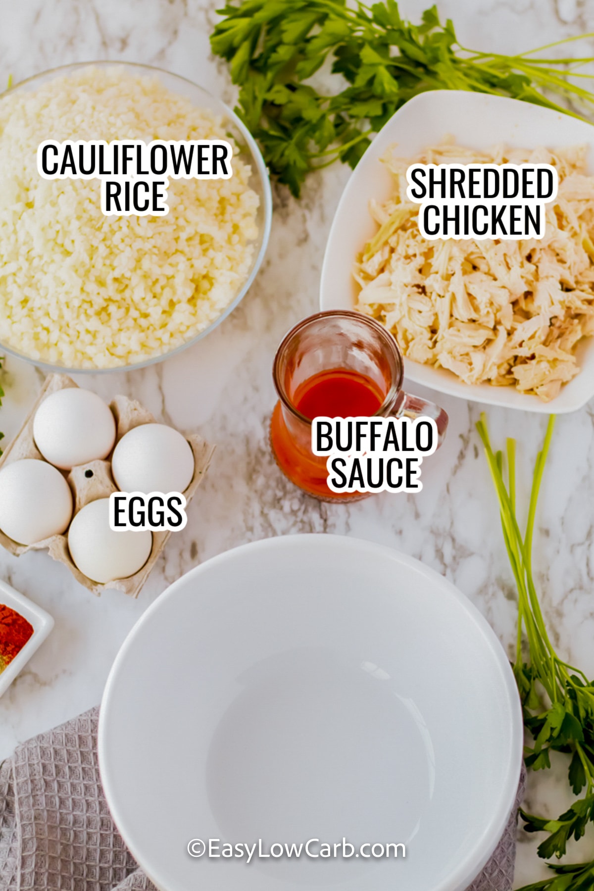 ingredients assembled to make keto buffalo chicken casserole including cauliflower rice, shredded chicken, eggs, and buffalo sauce
