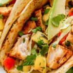grilled fish tacos topped with cilantro with text