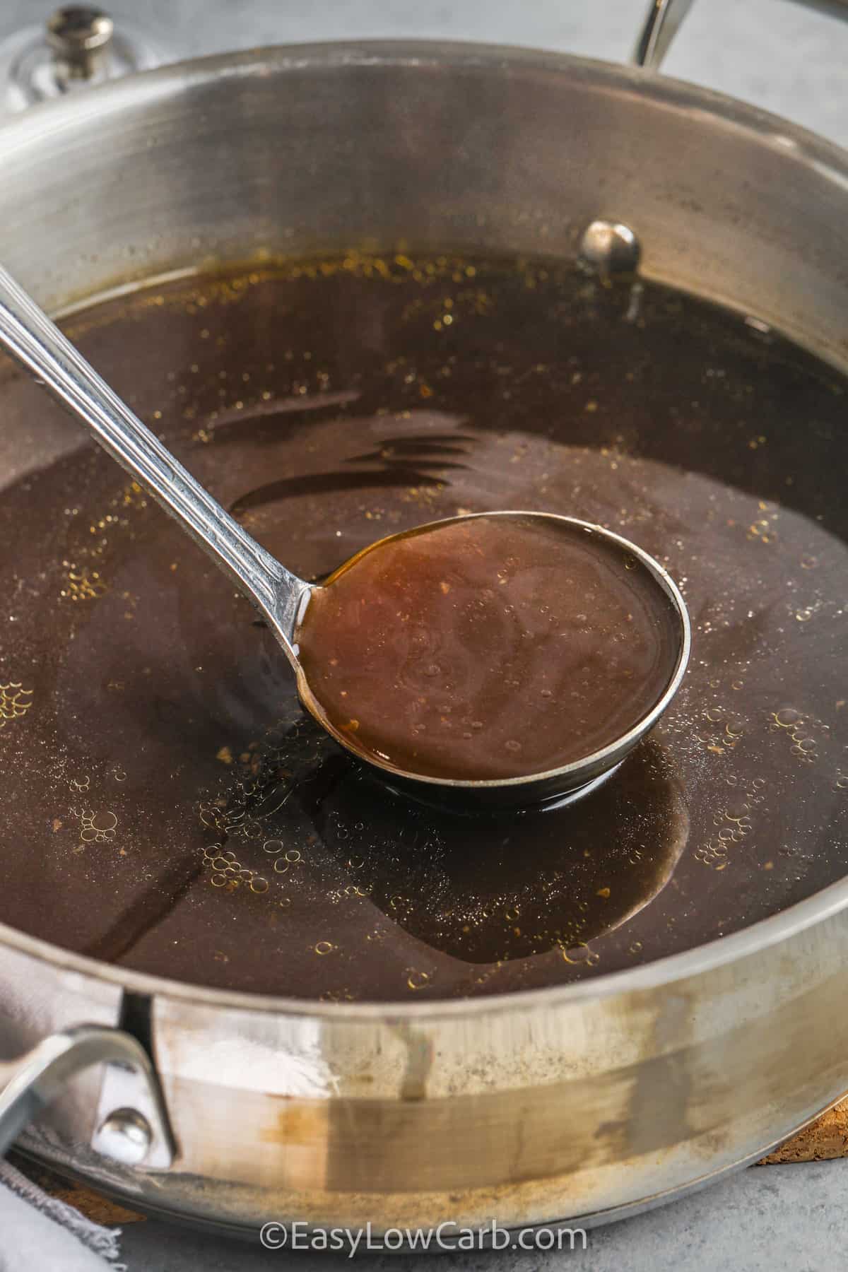 beef bone broth recipe in a pan, with a silver ladle scooping some broth out