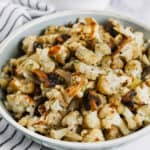 Cauliflower Stuffing in a bowl with a cup of gravy beside it