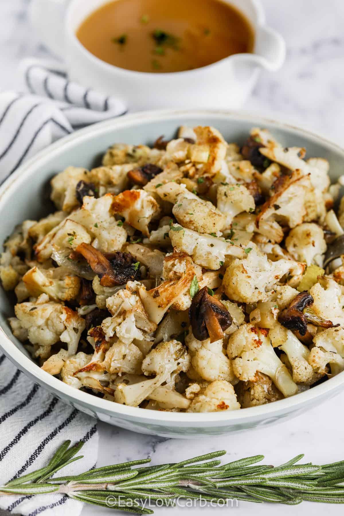 Cauliflower Stuffing in a bowl with a cup of gravy beside it