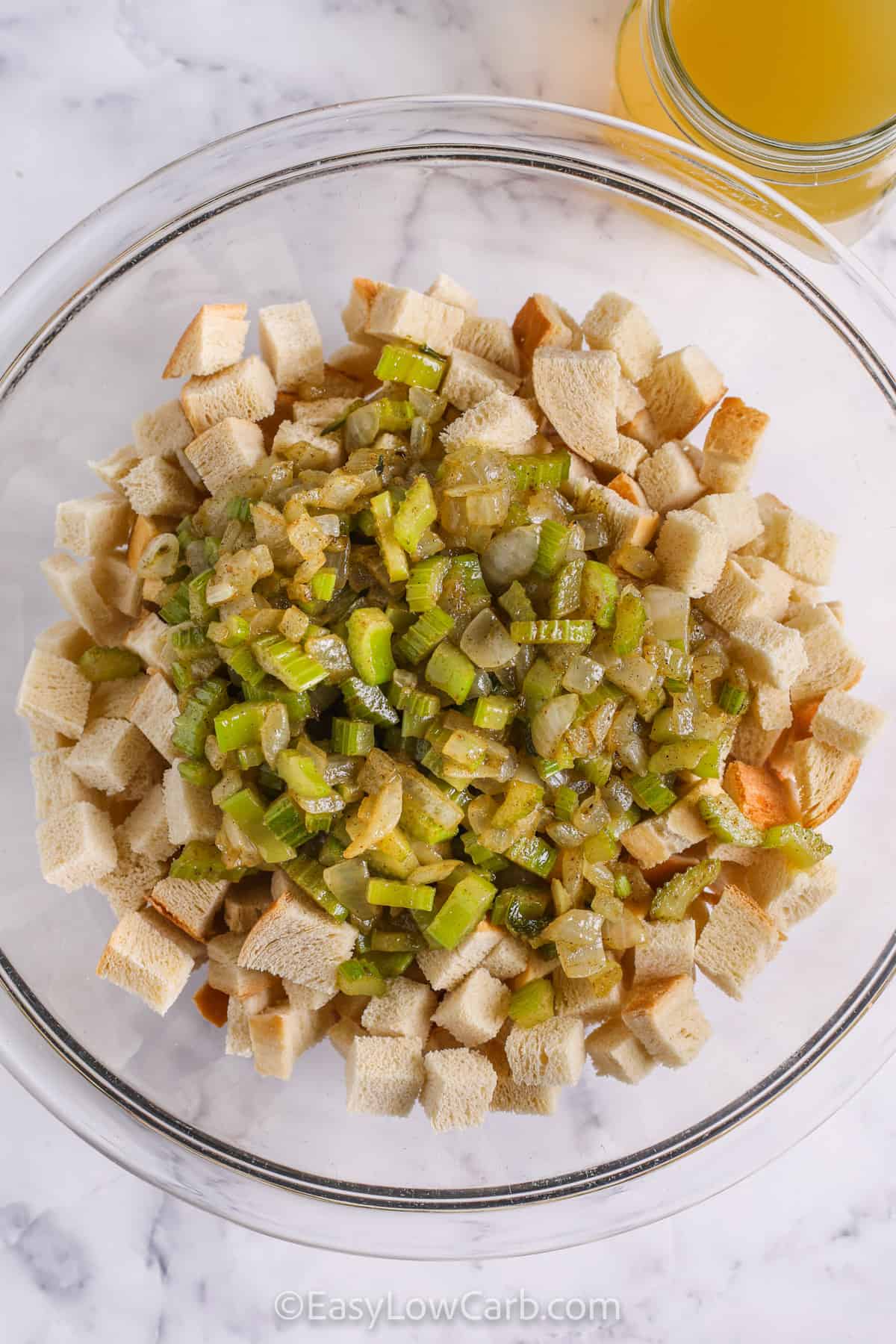 Keto stuffing features crisp toasted keto bread cubes tossed with onions, celery, poultry seasoning, and fresh herbs. Savory chicken broth keeps it perfectly moist while baking to golden perfection. This low carb, easy recipe captures the flavors and aroma of traditional stuffing and is ideal for holiday meals, family gatherings, or Thanksgiving, making it a comforting side that’s sure to impress everyone at the table. #easylowcarb adding vegetables to bread to make Keto Stuffing