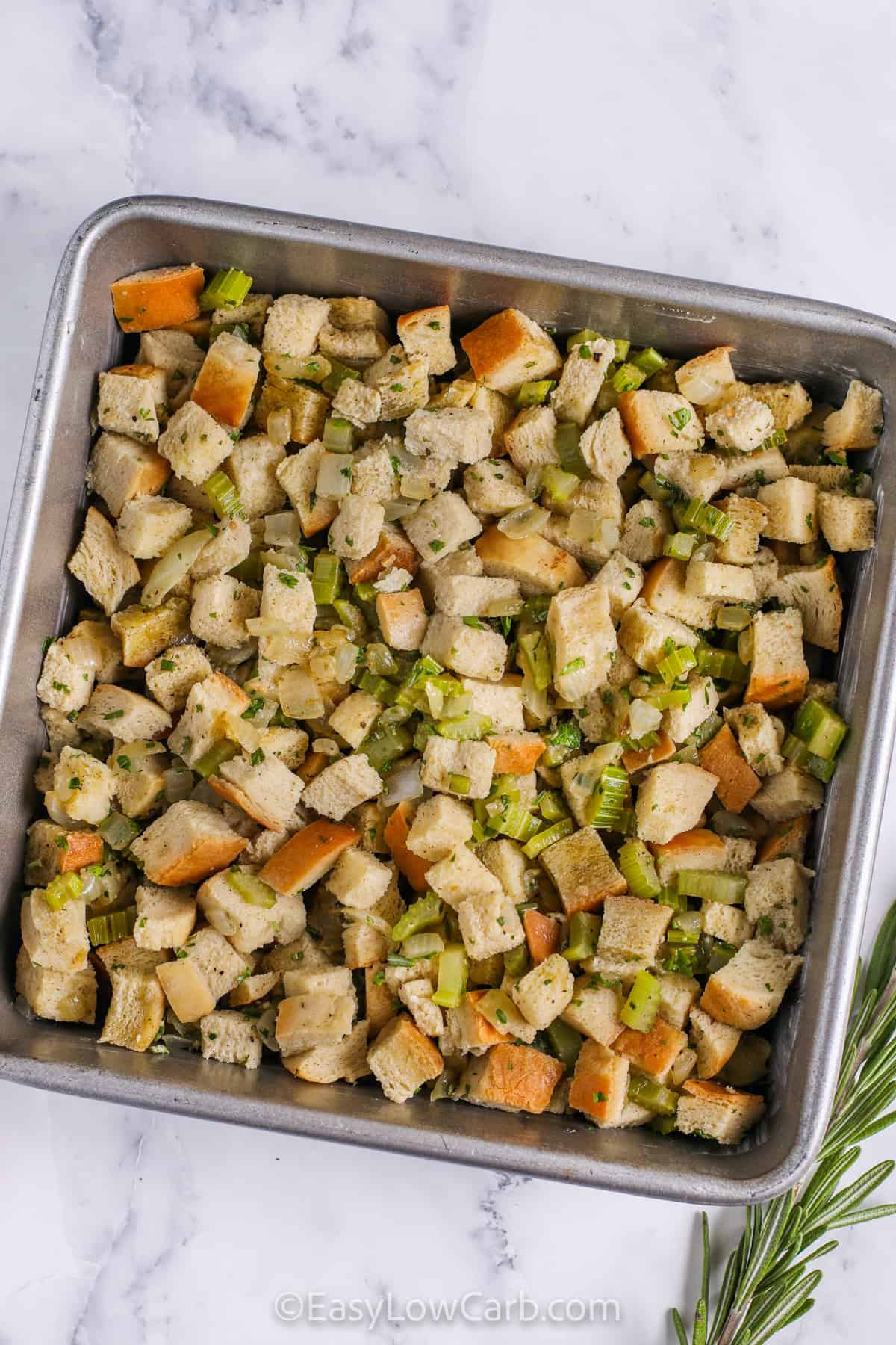 Keto stuffing combines buttery vegetables with toasted keto bread cubes, aromatic poultry seasoning, and fresh parsley and rosemary. Savory chicken broth binds it together, creating a moist, flavorful dish. Perfect for holiday dinners or Thanksgiving, this low carb recipe is easy to make and delivers all the traditional flavors of stuffing in a lighter, healthier version everyone will love. #easylowcarb Keto Stuffing in the pan before cooking-