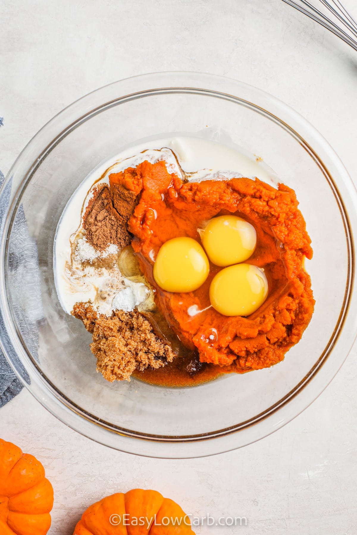 Keto pumpkin pie is smooth, flavorful, and perfect for holiday tables or everyday indulgence. The blend of eggs, heavy cream, and sweeteners creates a silky custard-like filling that pairs perfectly with your favorite keto whipped topping. Ready in no time, it’s easy to enjoy the seasonal flavor of pumpkin while staying on track. #easylowcarb wet ingredients with sugar and spices in a bowl to make Keto Pumpkin Pie Recipe