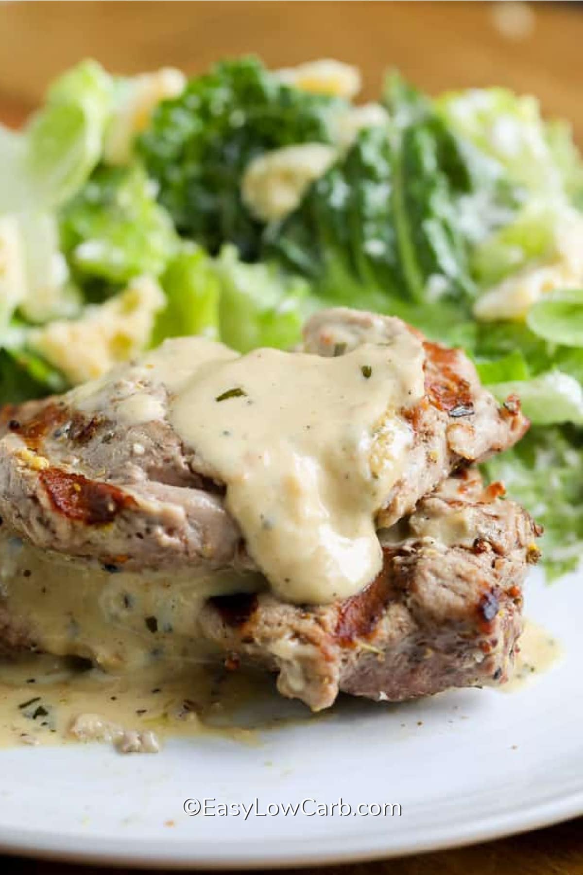 Creamy Dijon Pork Medallions served on a plate with salad in the background