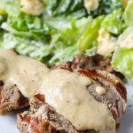 Creamy Dijon Pork Medallions on a white plate with salad in the background