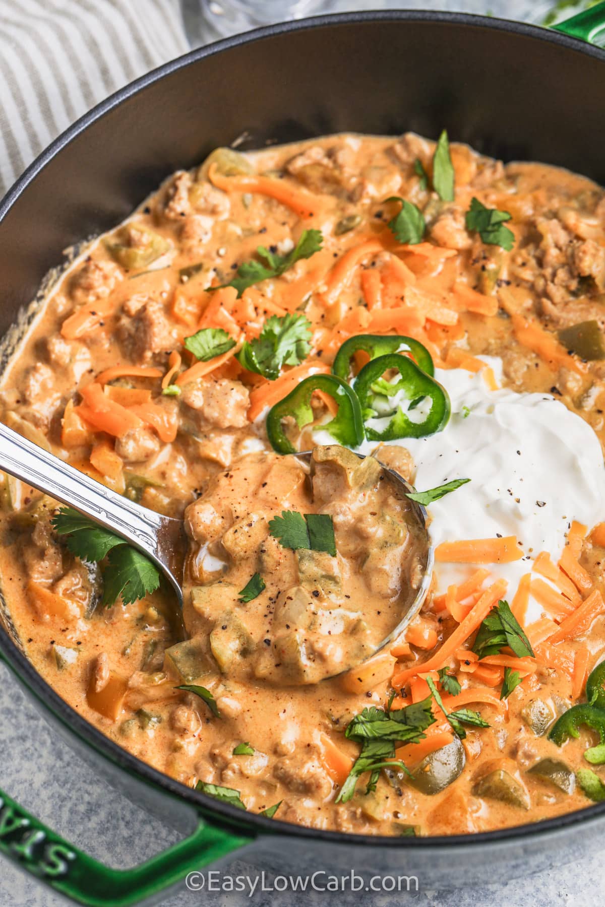 taking a spoonful of Keto White Chicken Chili out of the pan