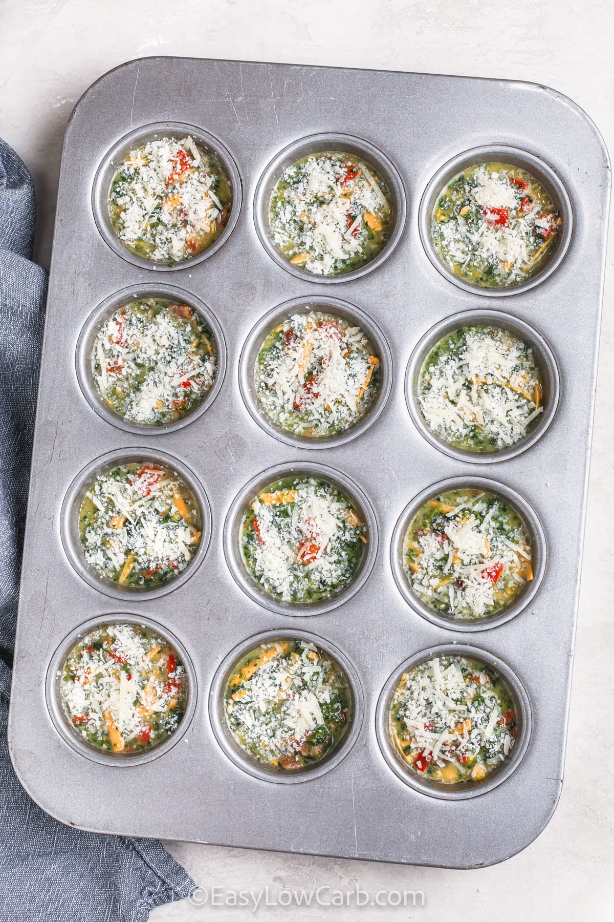 adding parmesan to Mini Quiches in muffin tin before cooking