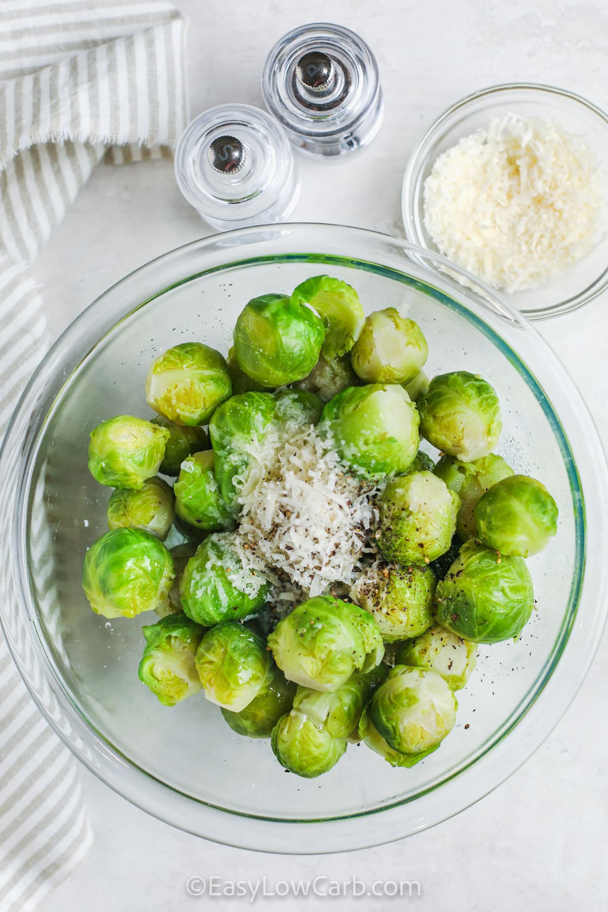 boiled brussels sprouts in a bowl with parmesan, salt, and pepper added in to make Smashed Brussel Sprouts Recipe