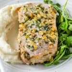 close up of air fryer pork chop resting on a bed of mashed potatoes with arugula on the side