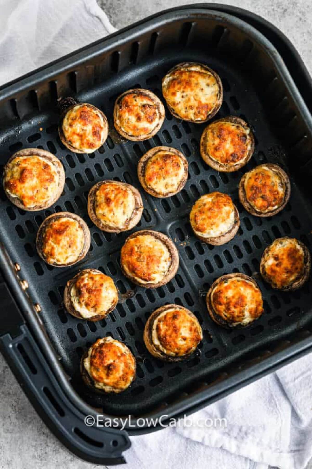 cooked and golden air fryer stuffed mushrooms in the bottom of an air fryer basket