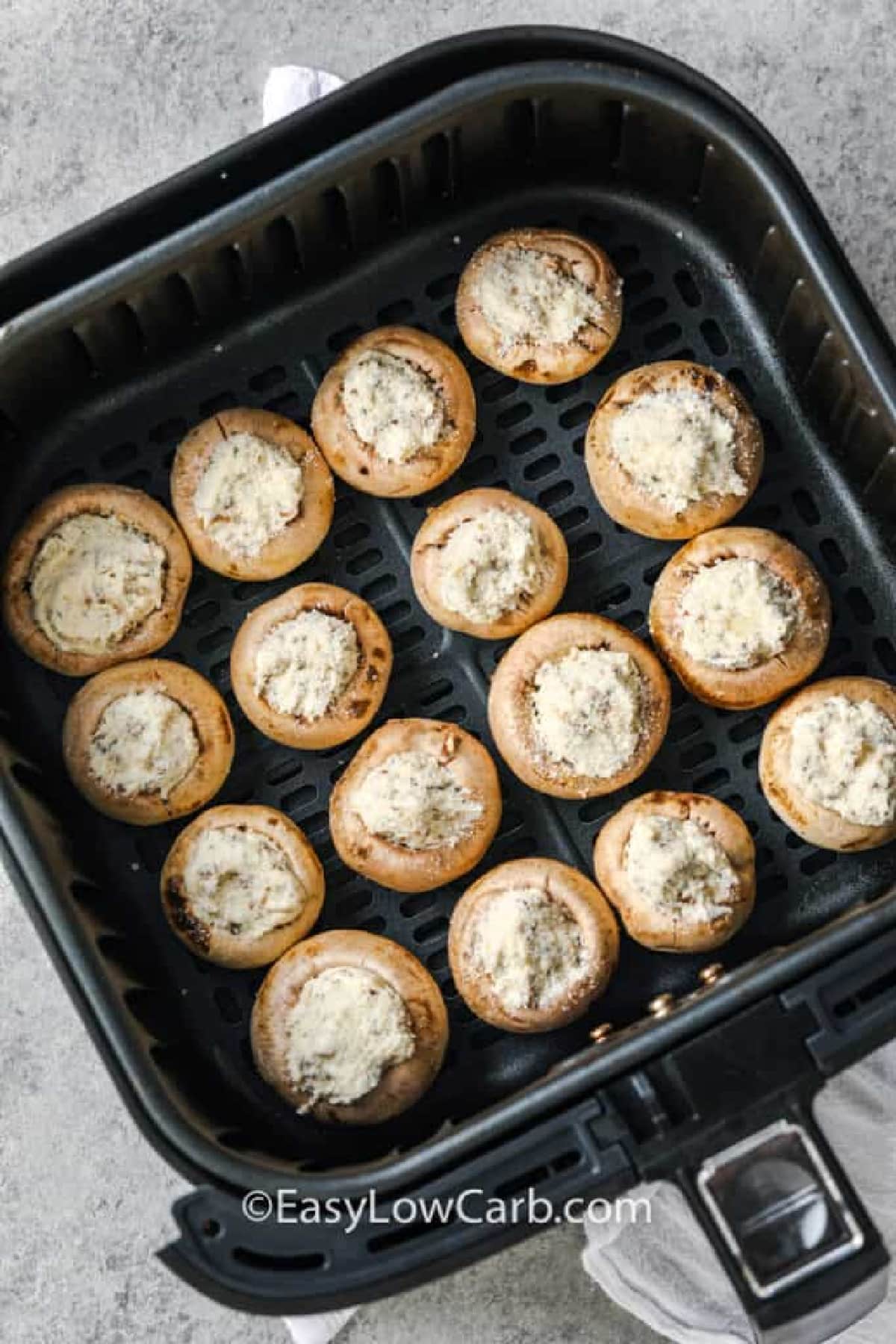 uncooked air fryer stuffed mushrooms in the bottom of an air fryer basket