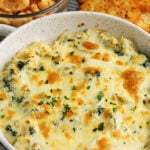 baked artichoke spinach dip in a dish with low carb dippers in the background