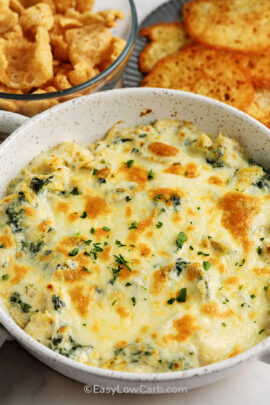 baked artichoke spinach dip in a dish with low carb dippers in the background