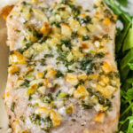 close up of air fryer pork chop resting on a bed of mashed potatoes with arugula on the side with a title