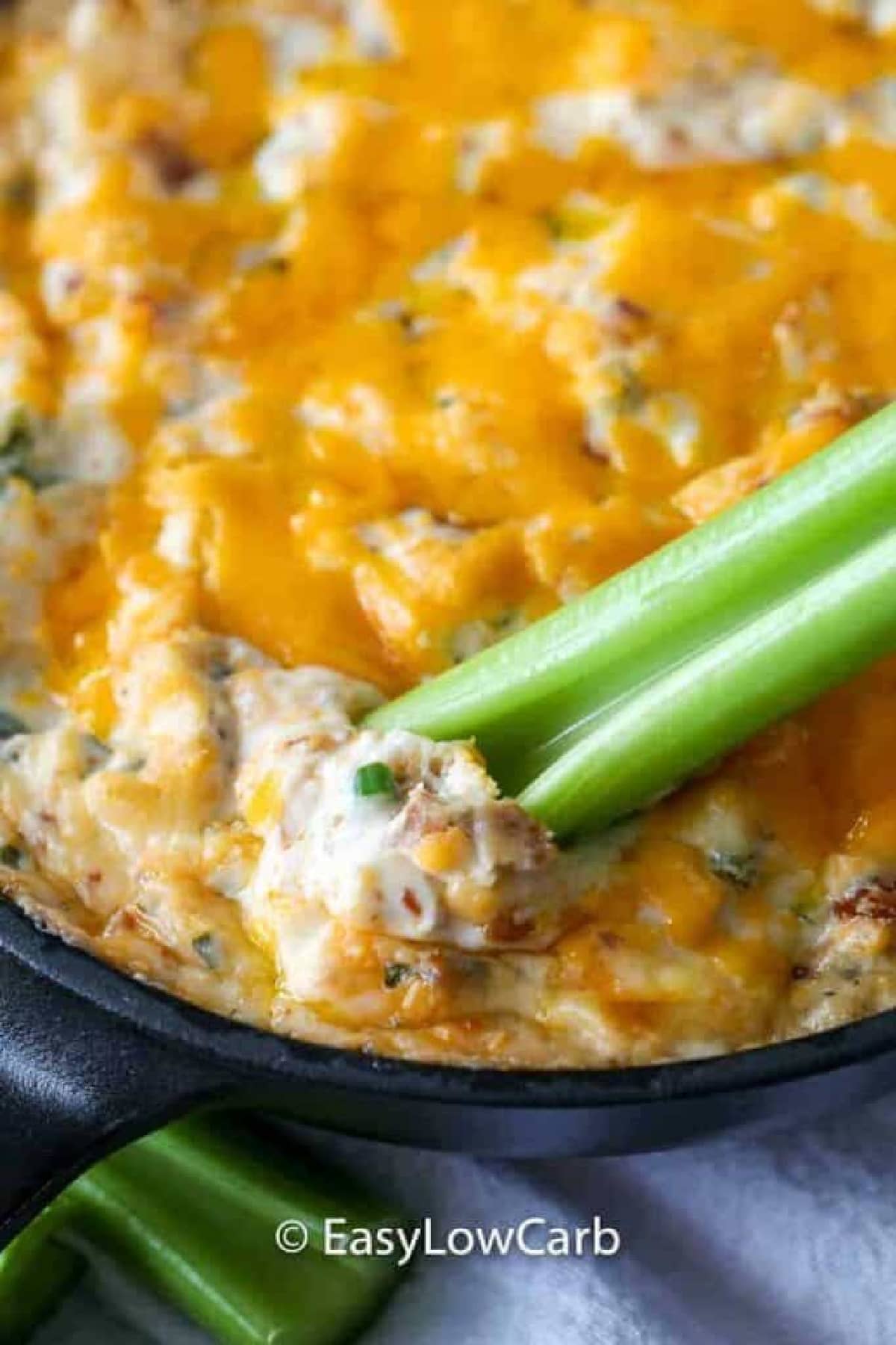 warm bacon dip in a skillet with a celery dipper