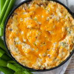 warm bacon dip in a cast iron skillet with celery sticks on the side