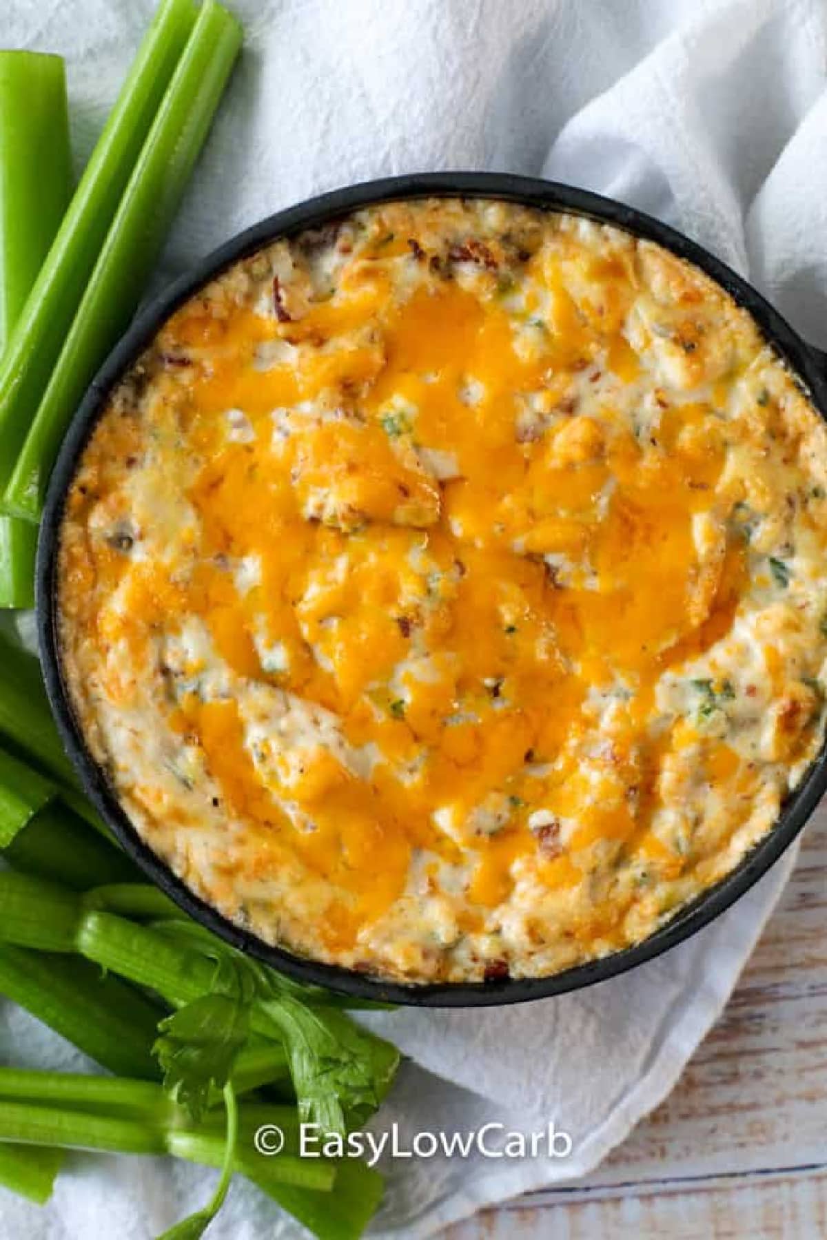 warm bacon dip in a cast iron skillet with celery sticks on the side