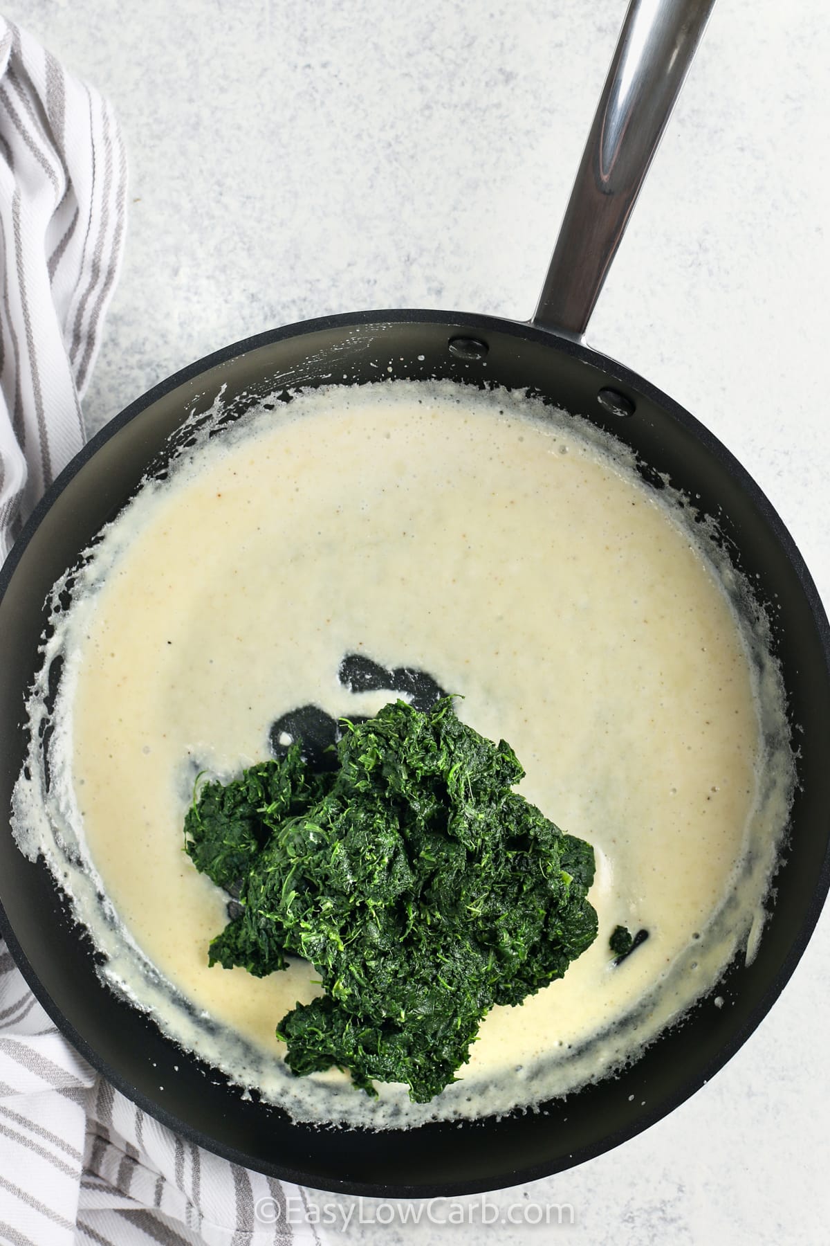 adding spinach to pan to make Easy Creamed Spinach