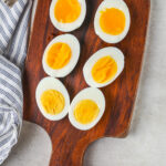 Easy Hard Boiled Eggs cooked in different intervals and cut in half on a cutting board