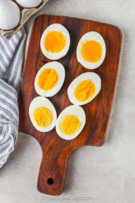 Easy Hard Boiled Eggs cooked in different intervals and cut in half on a cutting board