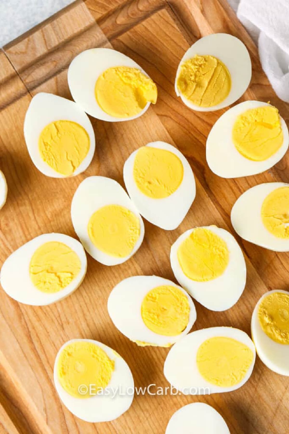 Hard boiled eggs cut in half and sitting on a wooden board ready to make Keto Deviled Eggs