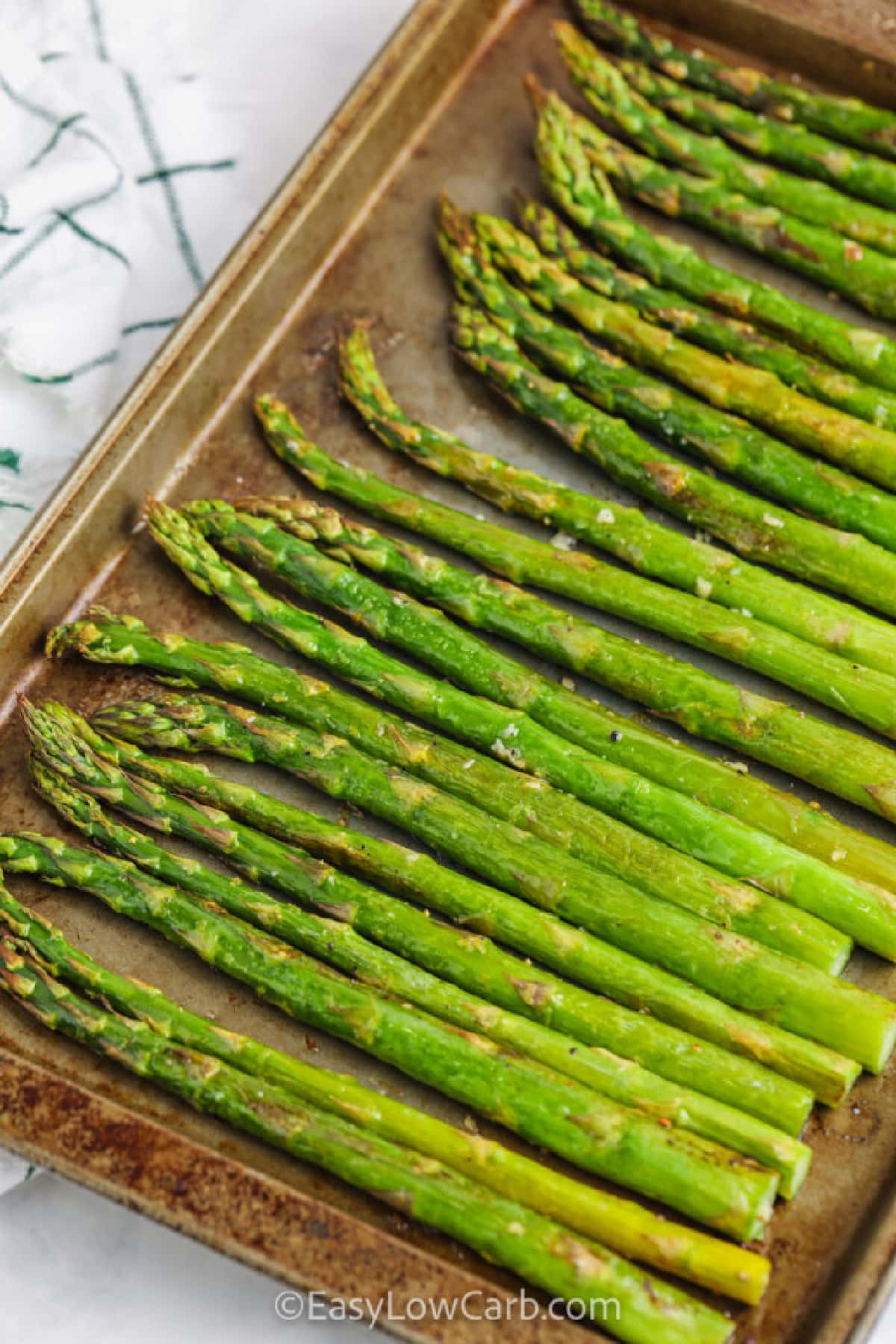 close up of oven-roasted asparagus with lemon in a single layer on a baking sheet