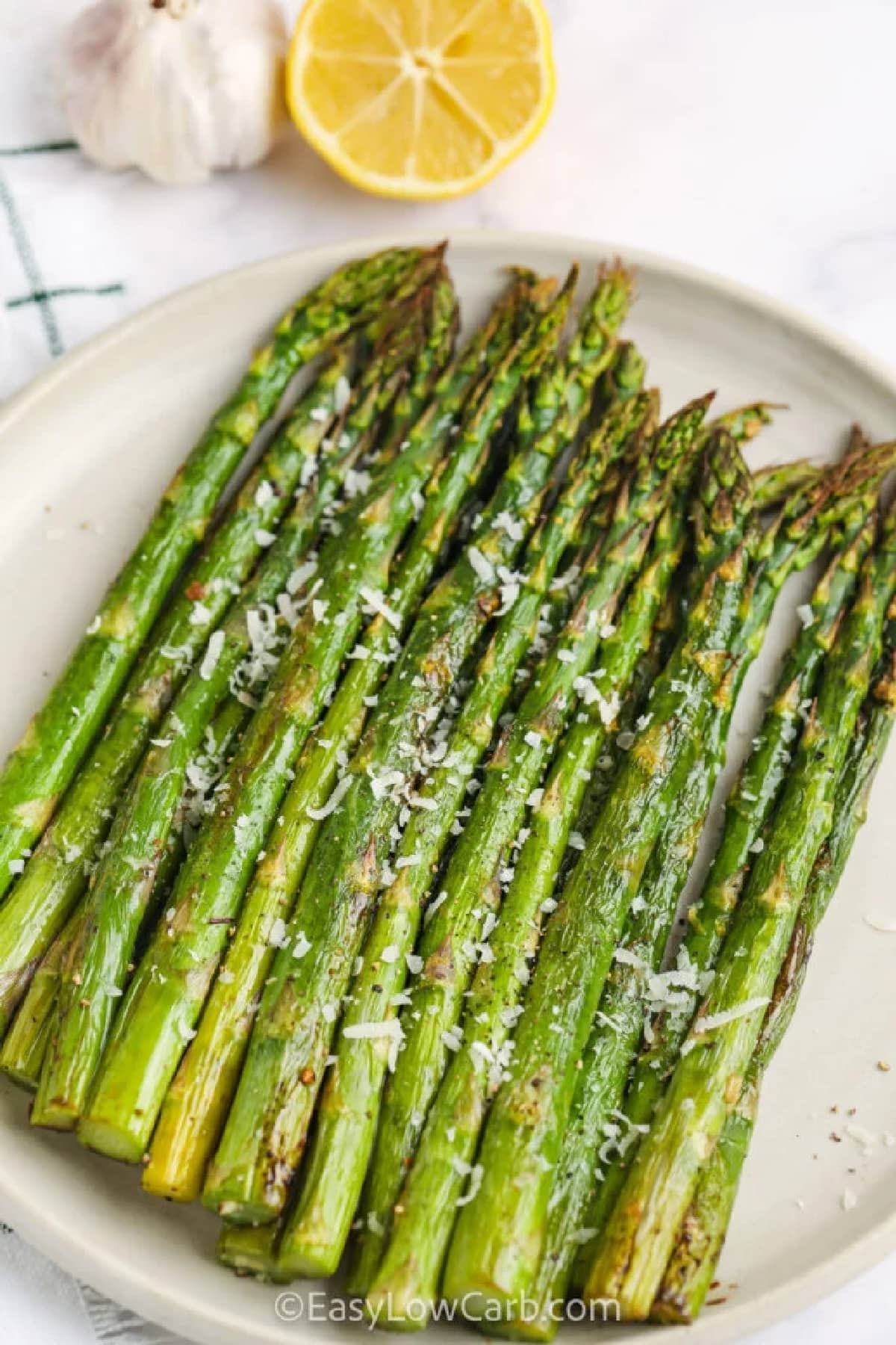 oven-roasted asparagus with lemon on a plate, with a sprinkle of parmesan cheese on top