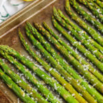 oven-roasted asparagus with lemon, in a single layer on a baking sheet, with a sprinkle of parmesan cheese on top