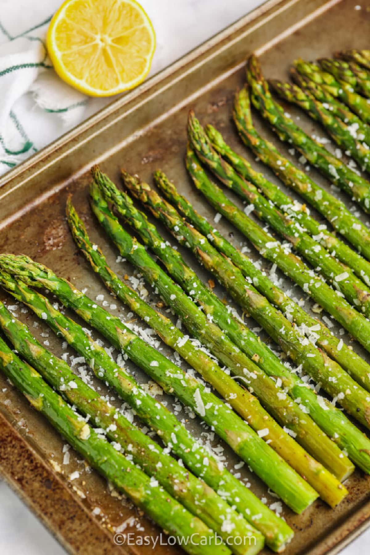 oven-roasted asparagus with lemon, in a single layer on a baking sheet, with a sprinkle of parmesan cheese on top