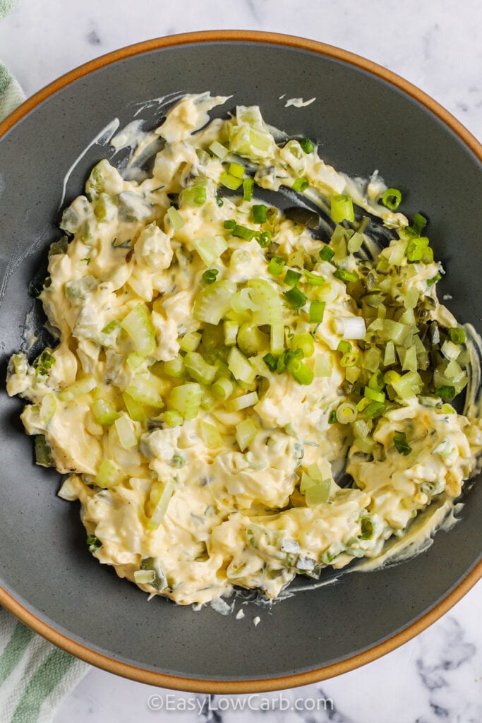 adding celery and pickles to eggs to make Tuna Egg Salad
