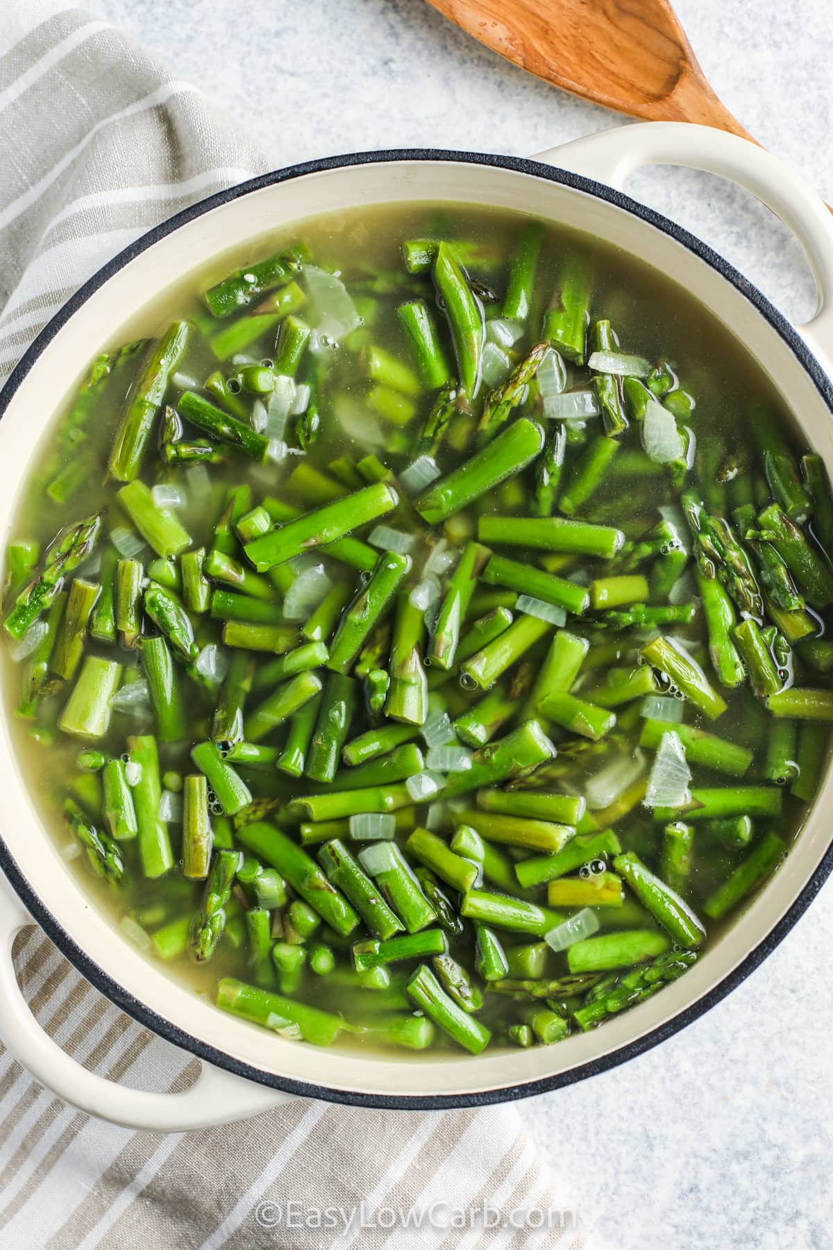 cut asparagus in a pot with water and onions to make Creamy Asparagus Soup