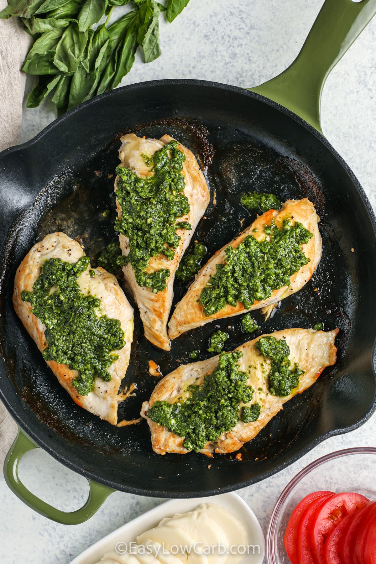 My Caprese chicken recipe turns everyday chicken breasts into a fresh and satisfying dinner. Layers of basil pesto, melted mozzarella cheese, sliced tomatoes, and balsamic add classic Italian flavor without complicated prep. This low carb skillet meal is great for weeknights and leftovers taste just as delicious the next day. Pair it with a simple salad or roasted vegetables for a complete dinner everyone will ask for again. Make this recipe tonight. #easylowcarb adding pesto to chicken to make Caprese Chicken Recipe