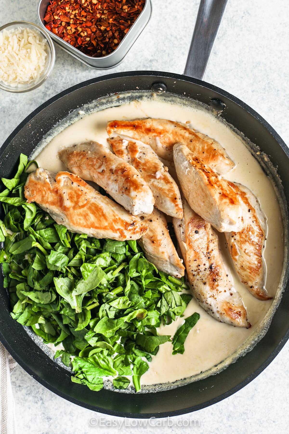 adding chicken and spinach to pan to make Creamy Spinach Chicken