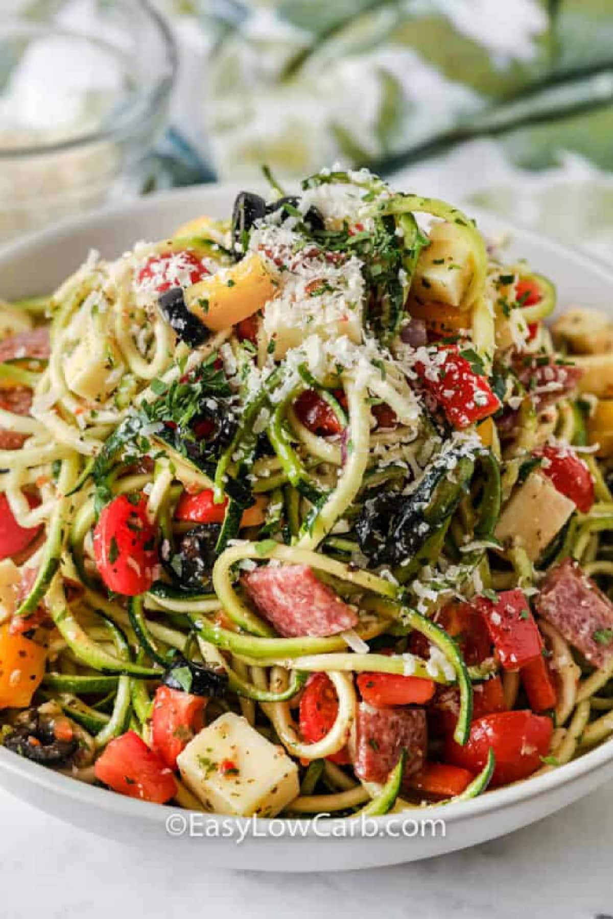 Zucchini Pasta Salad in a white bowl garnished with shredded parmesan