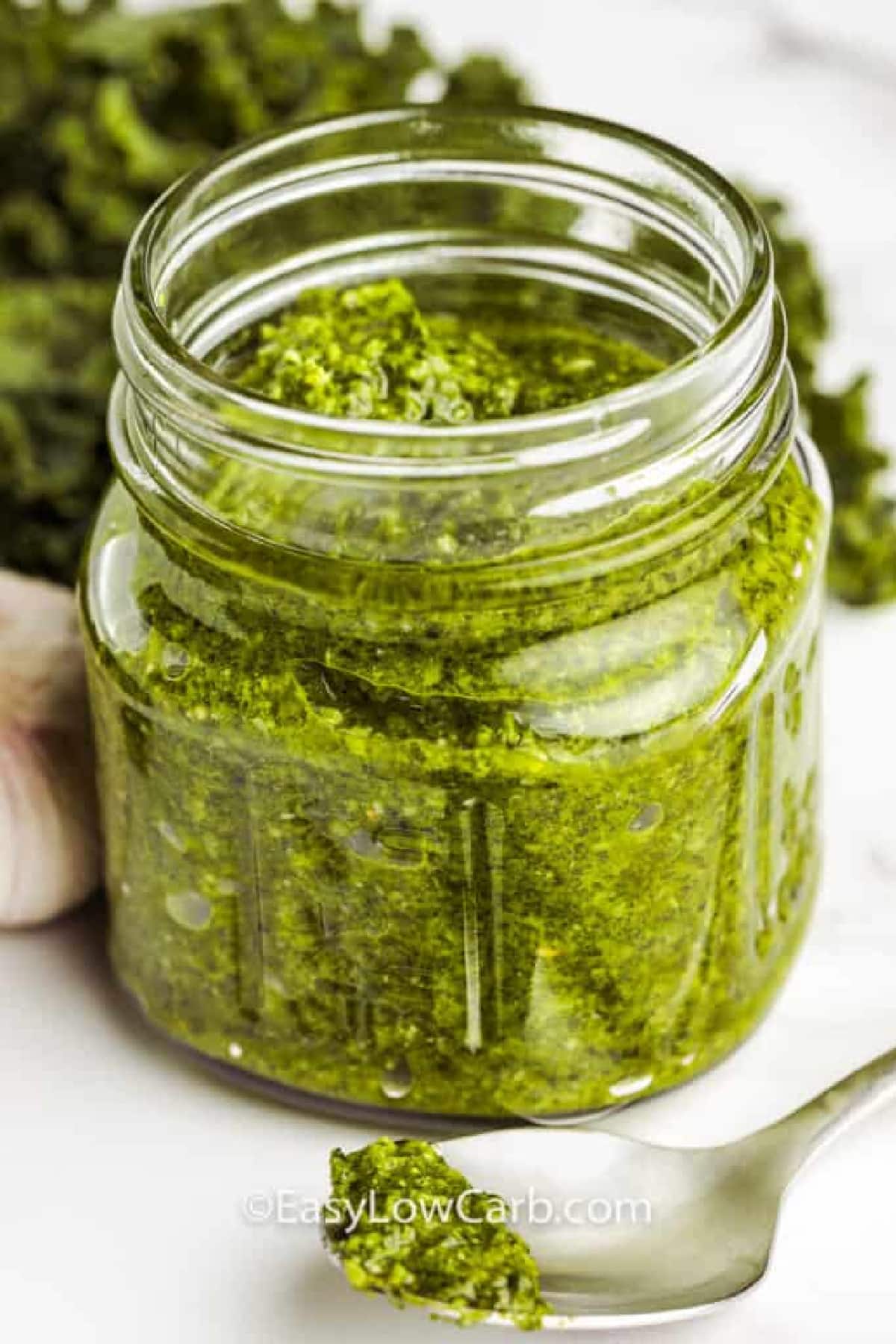 Kale pesto recipe in a jar with ingredients surrounding it