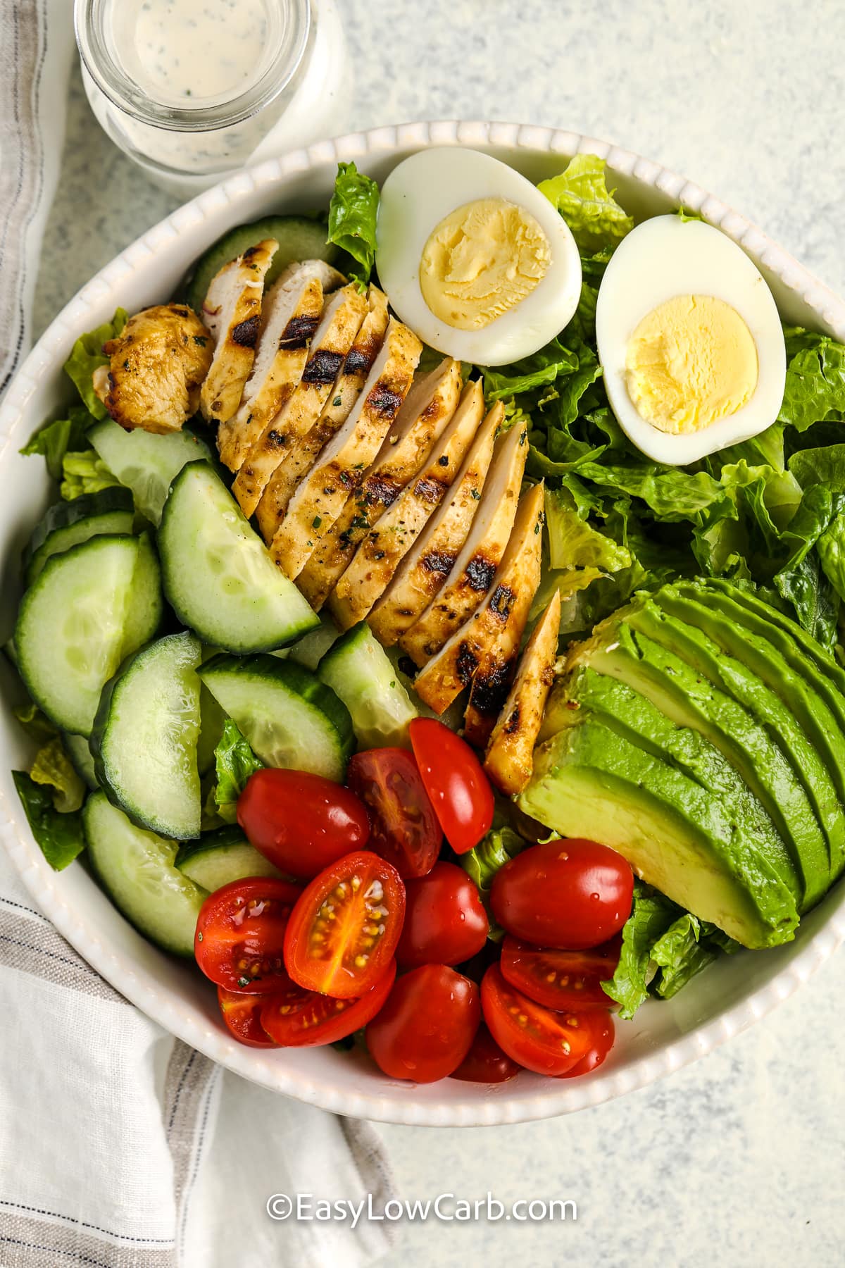 top view of grilled chicken salad in a white bowl