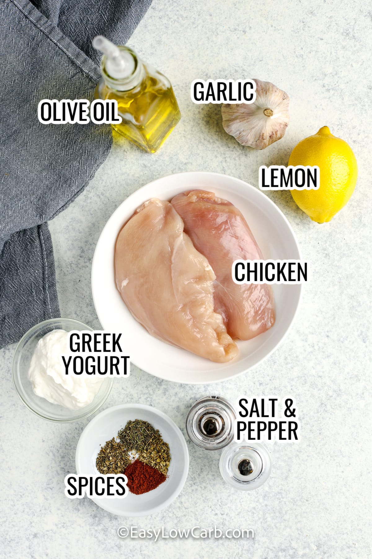 ingredients for greek yogurt chicken, including chicken, garlic, lemon, olive oil, greek yogurt, spices, and salt and pepper