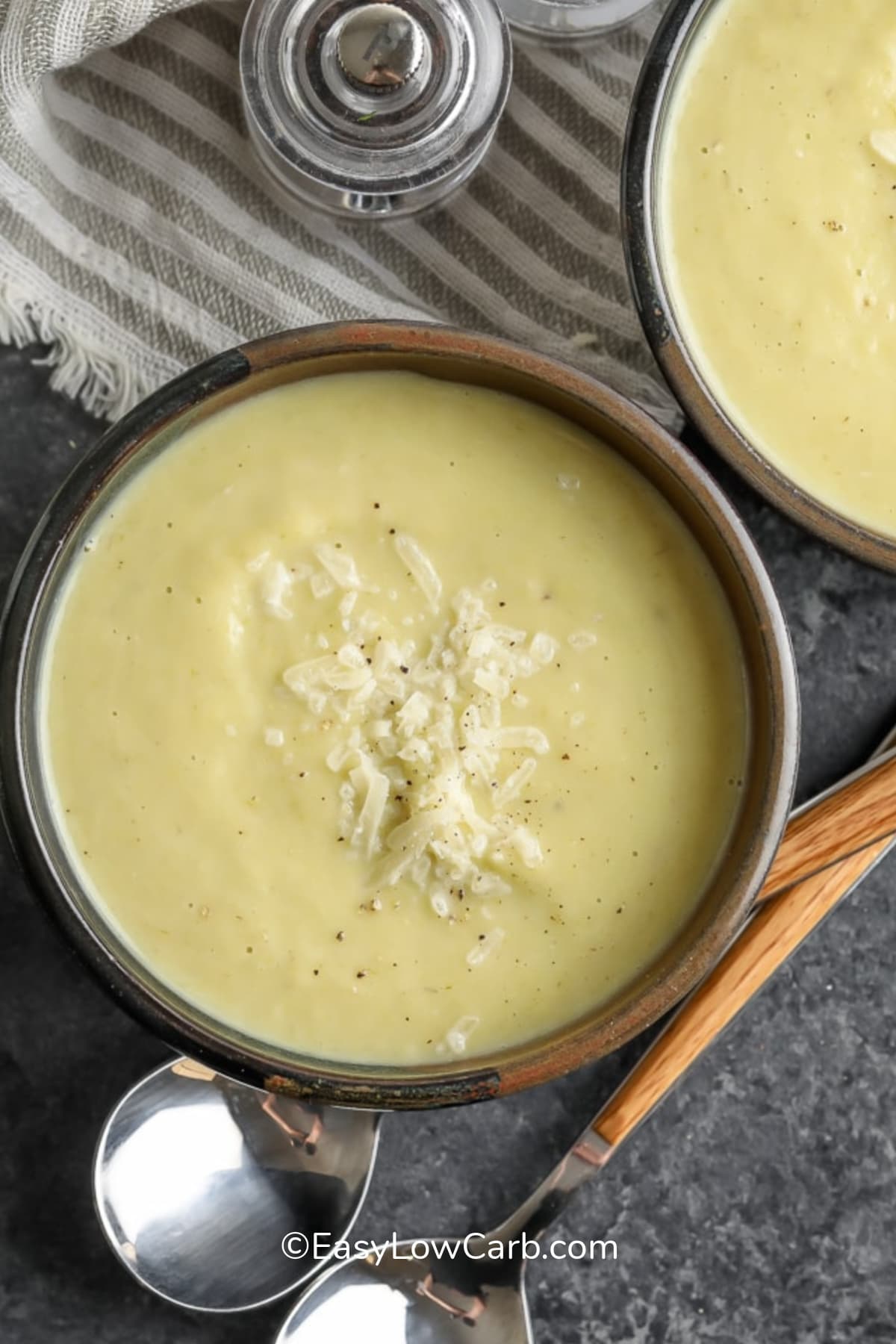 two bowls of cauliflower leek soup garnished with grated parmesan cheese