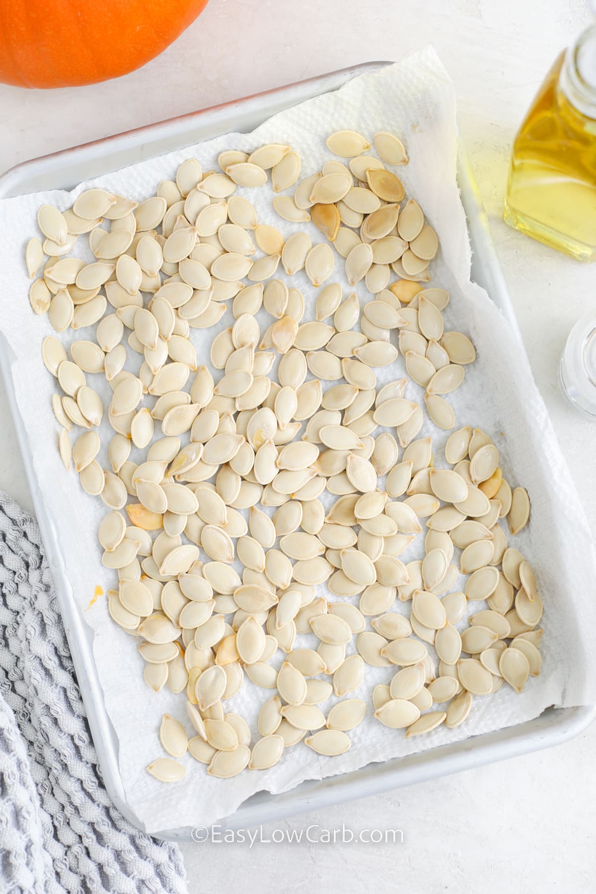 pumpkin seeds drying on paper towel in a baking sheet