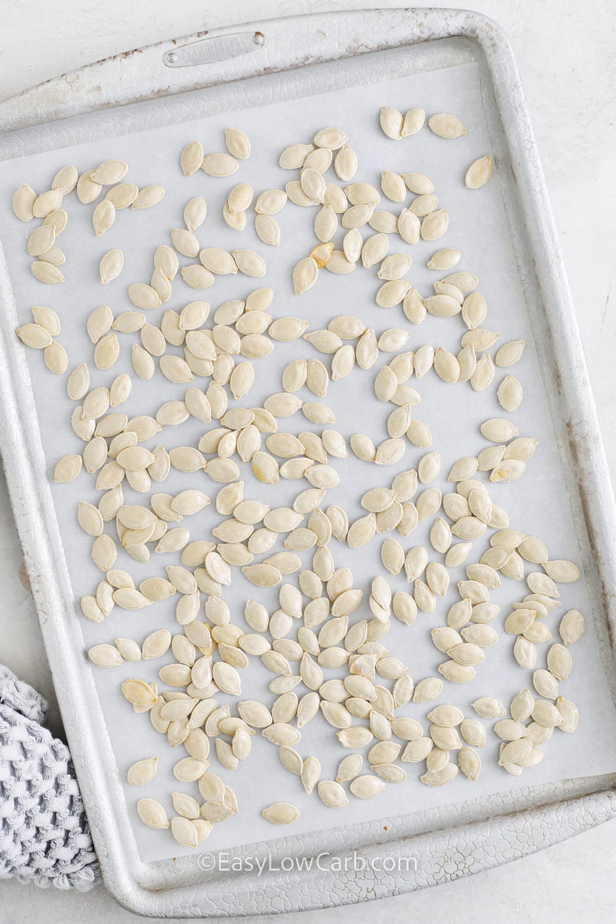 unbaked pumpkin seeds on a sheet pan