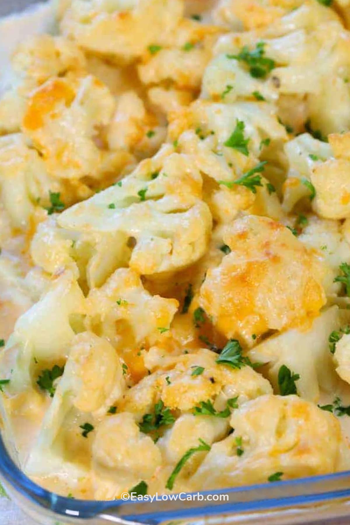 Close up of cheesy cauliflower casserole in a clear baking dish