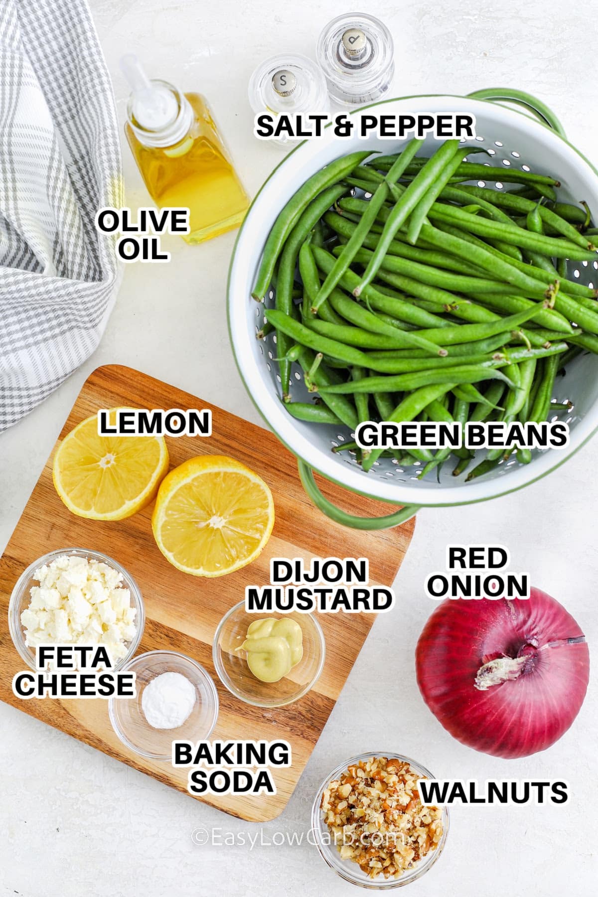 ingredients to make green bean salad labeled: green beans, olive oil, salt and pepper, lemon, feta cheese, dijon mustard, baking soda, red onion, and walnuts