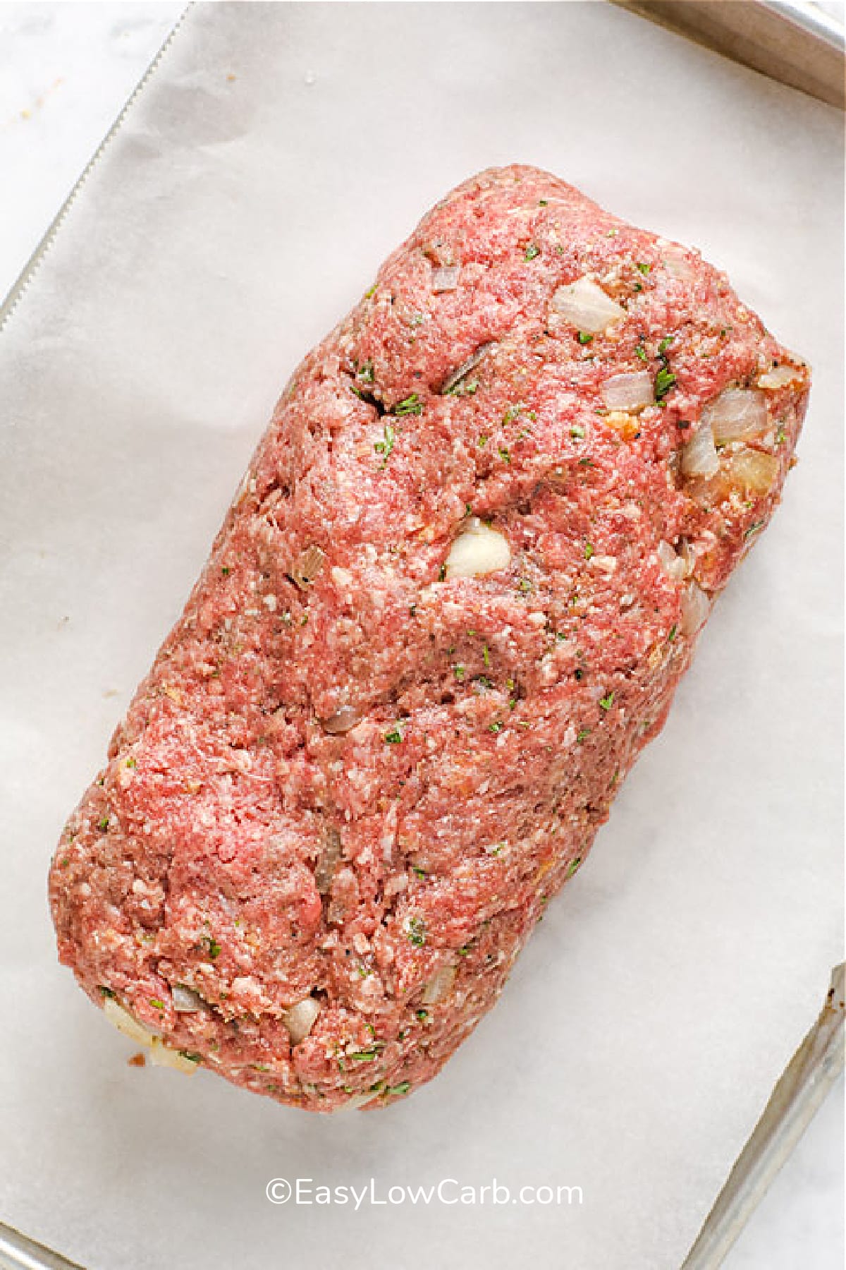 Low carb meatloaf, on a parchment lined tray, before cooking