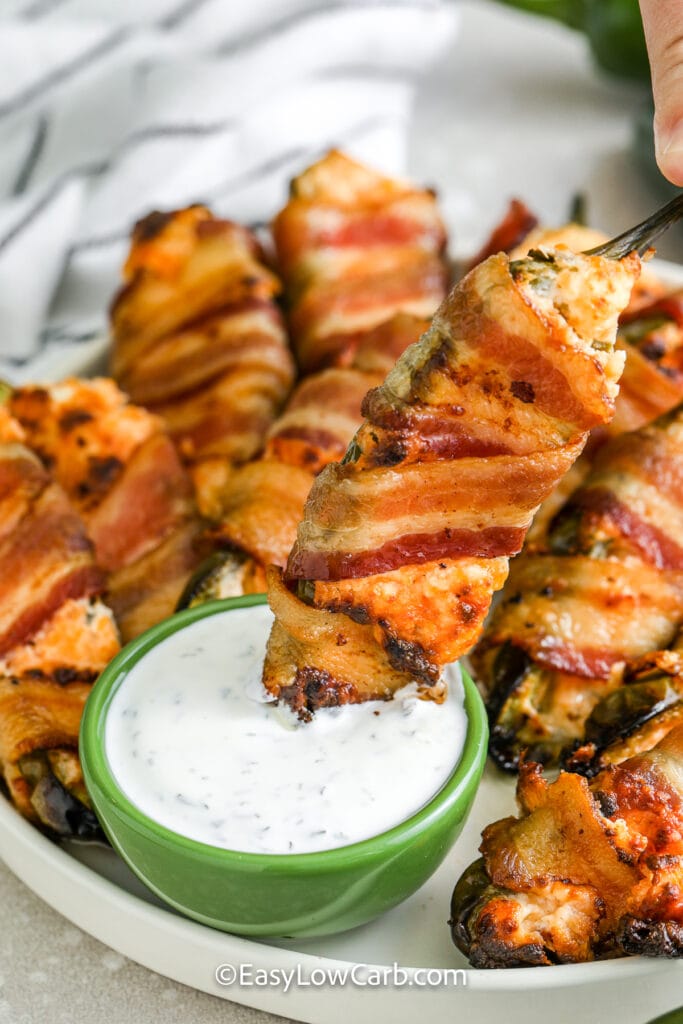 dipping bacon wrapped jalapenos into sauce