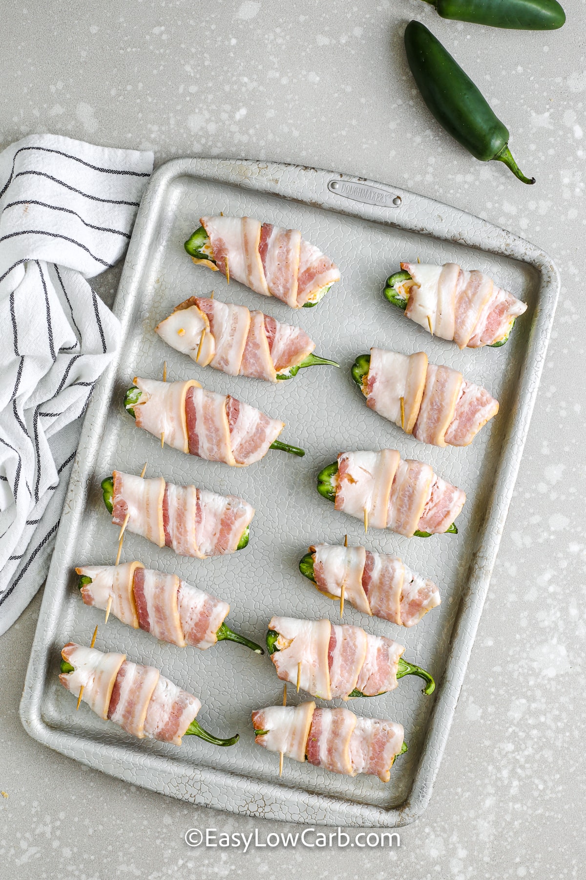 unbaked bacon wrapped jalapenos on a baking sheet
